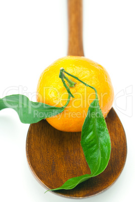 mandarin with green leaves on a wooden spoon isolated on white