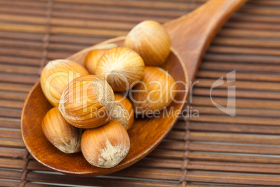 hazelnuts on a wooden spoon on a bamboo mat