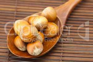 hazelnuts on a wooden spoon on a bamboo mat
