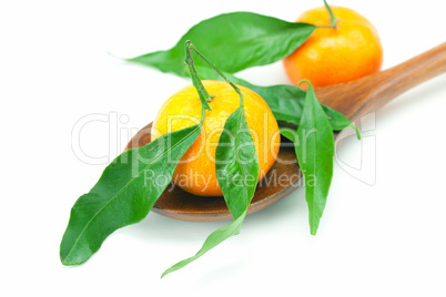 mandarin with green leaves on a wooden spoon isolated on white