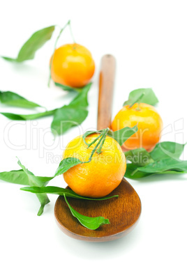 mandarin with green leaves on a wooden spoon isolated on white