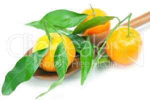 mandarin with green leaves on a wooden spoon isolated on white