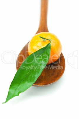 mandarin with green leaves on a wooden spoon isolated on white