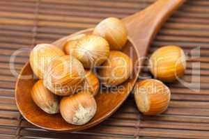 hazelnuts on a wooden spoon on a bamboo mat
