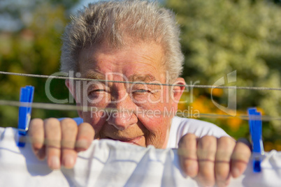 Senior hängt ein Bettlaken auf