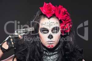 Young girl in day of the dead mask with gun