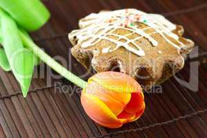 cake with icing and a tulip lying on a bamboo mat