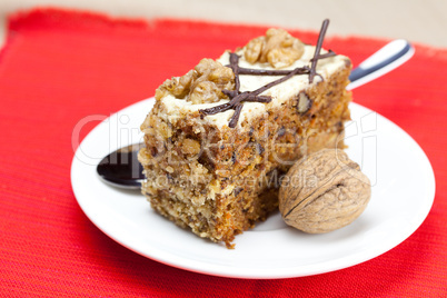 Piece of cake with nuts and spoon lying on a plate