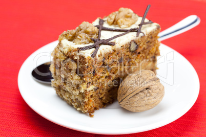 Piece of cake with nuts and spoon lying on a plate