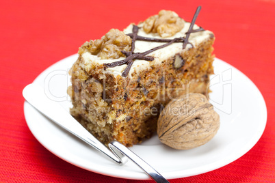 Piece of cake with nuts and spoon lying on a plate