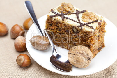 Piece of cake with nuts and spoon lying on a plate