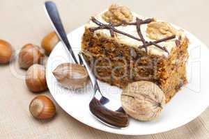 Piece of cake with nuts and spoon lying on a plate