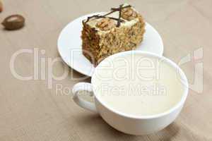 cup of cappuccino, a piece of cake with nuts lying on the plate