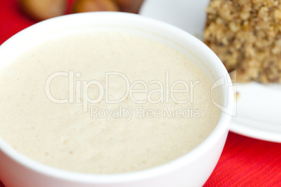 cup of cappuccino, a piece of cake with nuts on a plate lying on