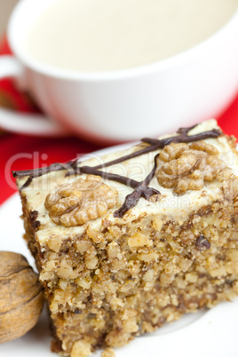 cup of cappuccino, a piece of cake with nuts on a plate lying on