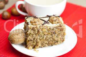 cup of cappuccino, a piece of cake with nuts on a plate lying on