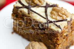 Piece of cake with nuts lying on the plate on a red background