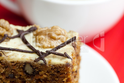 cup of cappuccino, a piece of cake with nuts on a plate lying on