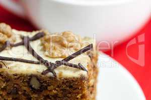 cup of cappuccino, a piece of cake with nuts on a plate lying on