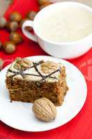 cup of cappuccino, a piece of cake with nuts on a plate lying on