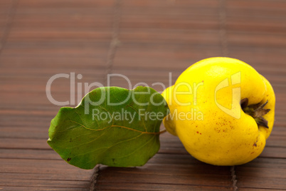 yellow quinces with a green leaf on a bamboo mat