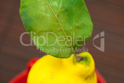 yellow quinces with green leaves in a cup on a bamboo mat