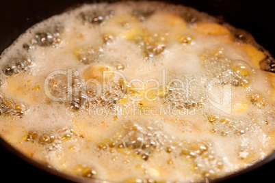 bananas in the pan in boiling caramel
