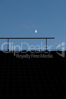 moon in the night sky above the roof