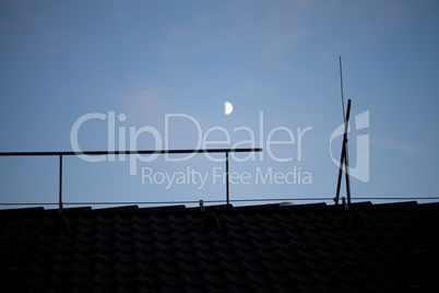 moon in the night sky above the roof