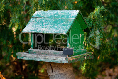 large birdhouse in a forest and a blackboard