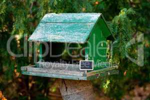 large birdhouse in a forest and a blackboard