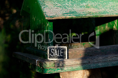 large birdhouse in a forest and a blackboard with the inscriptio