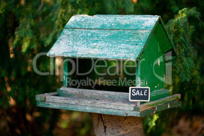 large birdhouse in a forest and a blackboard with the inscriptio
