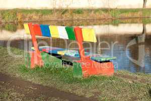 multi-colored bench standing in a park near the pond