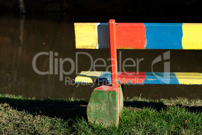 multi-colored bench standing in a park near the pond