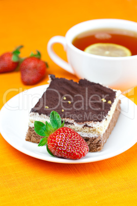 lemon tea, cake and strawberries lying on the orange fabric