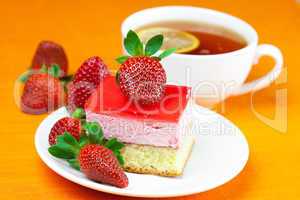 lemon tea, cake and strawberries lying on the orange fabric