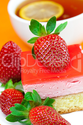 lemon tea, cake and strawberries lying on the orange fabric