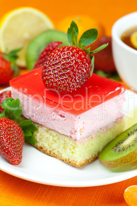 lemon tea, kiwi,cake and strawberries lying on the orange fabric