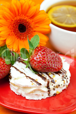 lemon tea,gerbera,cake and strawberries lying on the orange fabr