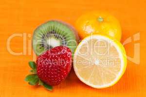kiwi,lemon,mandarin and strawberries lying on the orange fabric