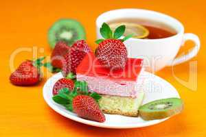 lemon tea, kiwi,cake and strawberries lying on the orange fabric