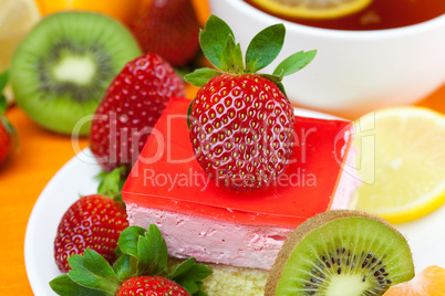 lemon tea, kiwi,cake and strawberries lying on the orange fabric