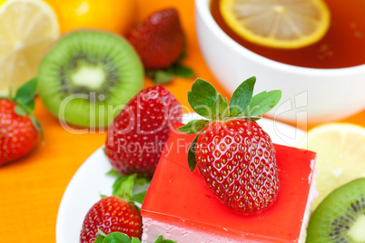 lemon tea, kiwi,cake and strawberries lying on the orange fabric