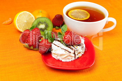 lemon tea,lemon, mandarin, kiwi,cake and strawberries lying on t