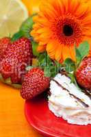 lemon ,gerbera,cake and strawberries lying on the orange fabric