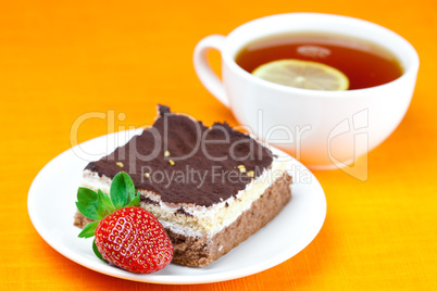 lemon tea, cake and strawberries lying on the orange fabric