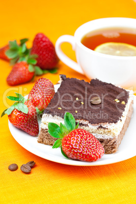 lemon tea, cake and strawberries lying on the orange fabric