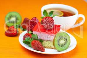 lemon tea, kiwi,cake and strawberries lying on the orange fabric