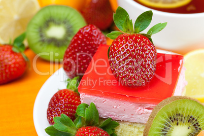 lemon tea, kiwi,cake and strawberries lying on the orange fabric